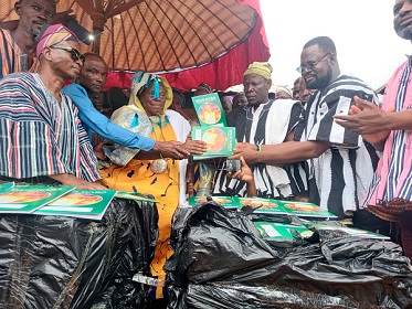Naa-Zoori Saaka Sulemana (middle), Paramount Chief of Wungu Traditional Area, presenting the exercise books to Simon Anane Amokase (right), the North East Regional Education Director